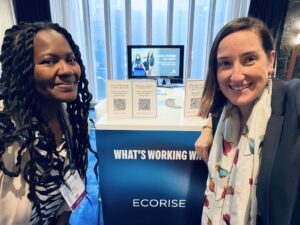 Zakhia Grant and Tara Cardone posing in front of the EcoRise What's Working Way table.